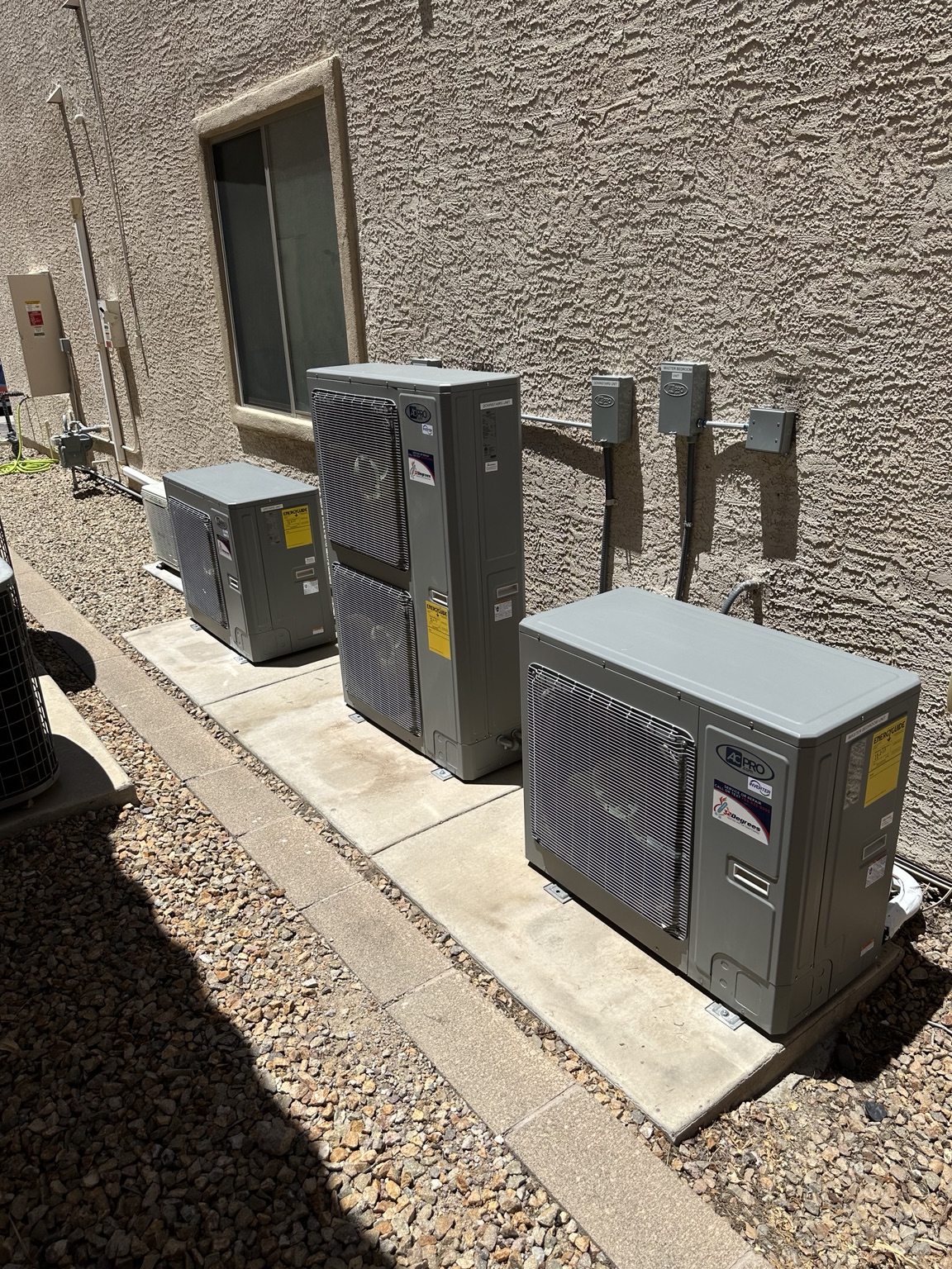 Three AC Pro outdoor units beside a home with 32 Degrees service labels.